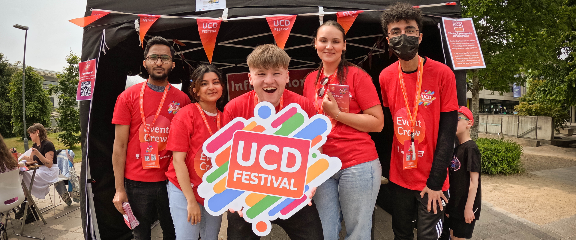 Five UCD Festival volunteers wearing red crew t-shirts, smiling at the camera.